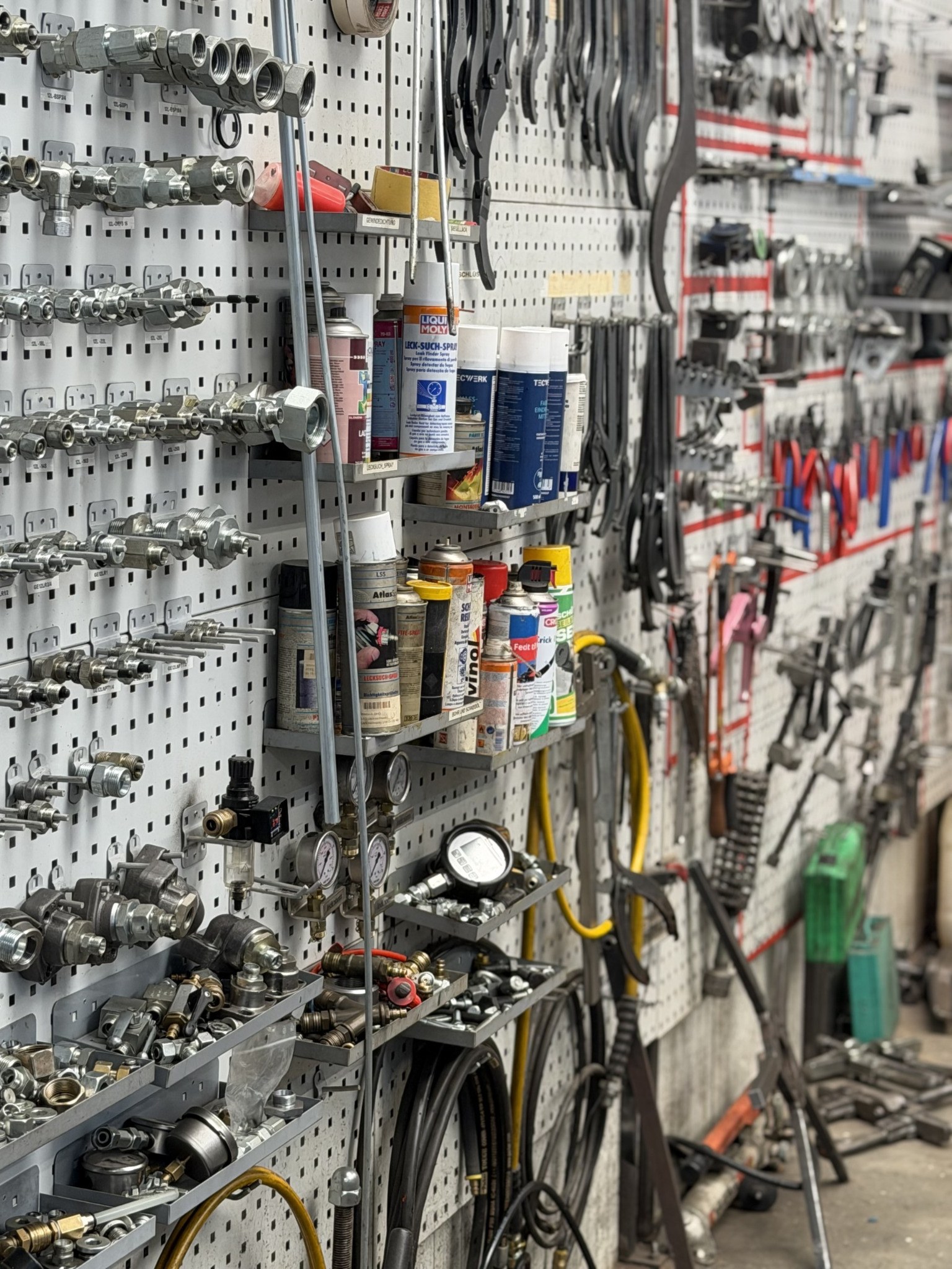 Werkstattwand bei Wiebeck mit Hydraulikkomponenten und Werkzeugen